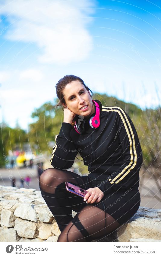 Portrait of a sporty young woman with headphones while exercising outdoors.  - a Royalty Free Stock Photo from Photocase