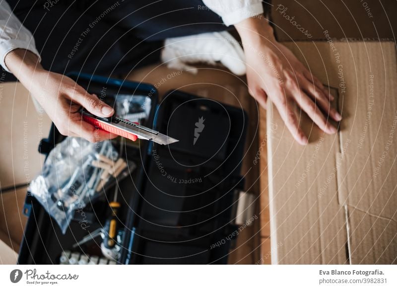 close up of young woman assembling furniture at home working with cutter. DIY concept do it yourself box carton screws nut house caucasian indoor renovation