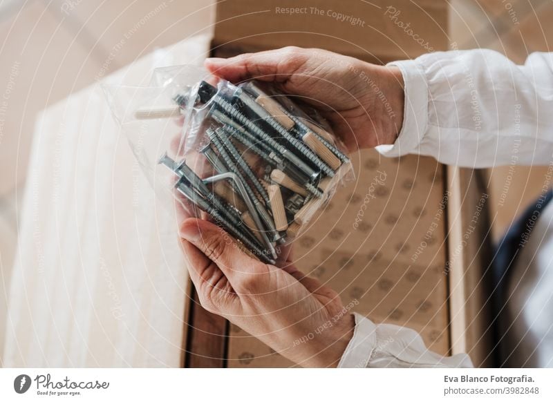close up of young woman assembling furniture at home working with screws and nuts. DIY concept do it yourself house caucasian indoor renovation young adult