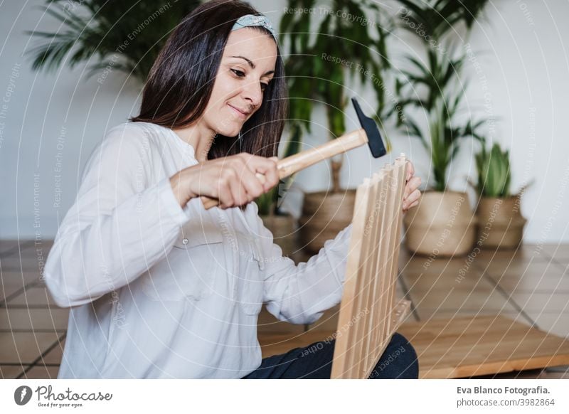 close up of young woman assembling furniture at home working with hammer. DIY concept do it yourself house caucasian indoor renovation young adult craft