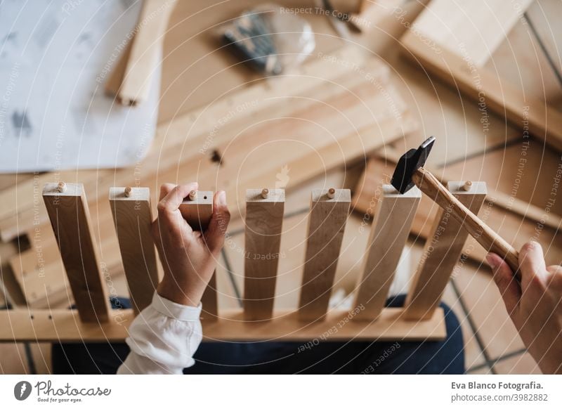 close up of young woman assembling furniture at home working with hammer. DIY concept. top view do it yourself house caucasian indoor renovation young adult