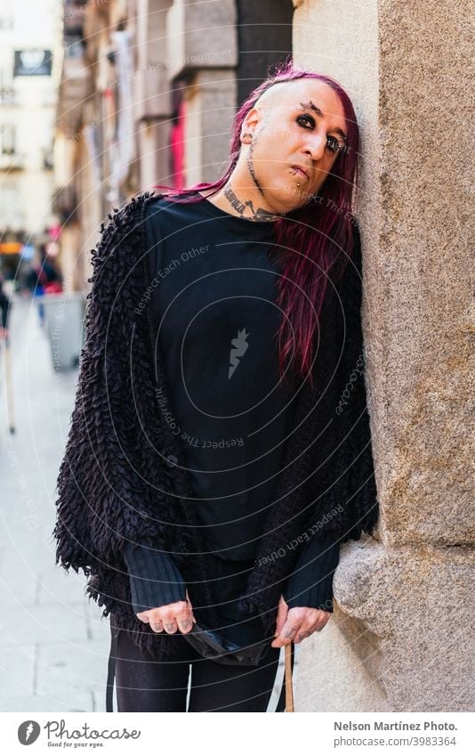 Portrait of an eccentric rocker wearing black clothes. He has tattoos and long purple hair. androgynous male beautiful young man feminine guy closeup gay