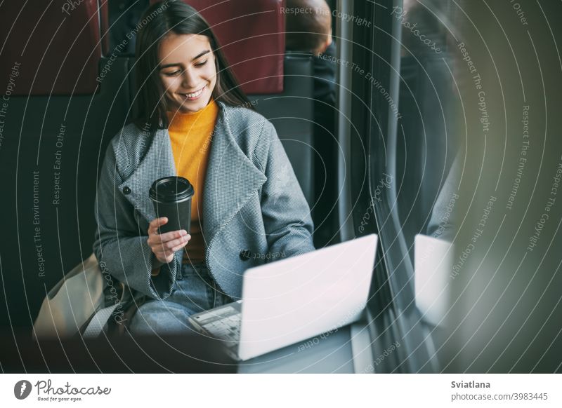 Freelance girl drinks coffee and sits on the train with a working laptop. Modern technologies and networks technology travel business freelancer phone concept