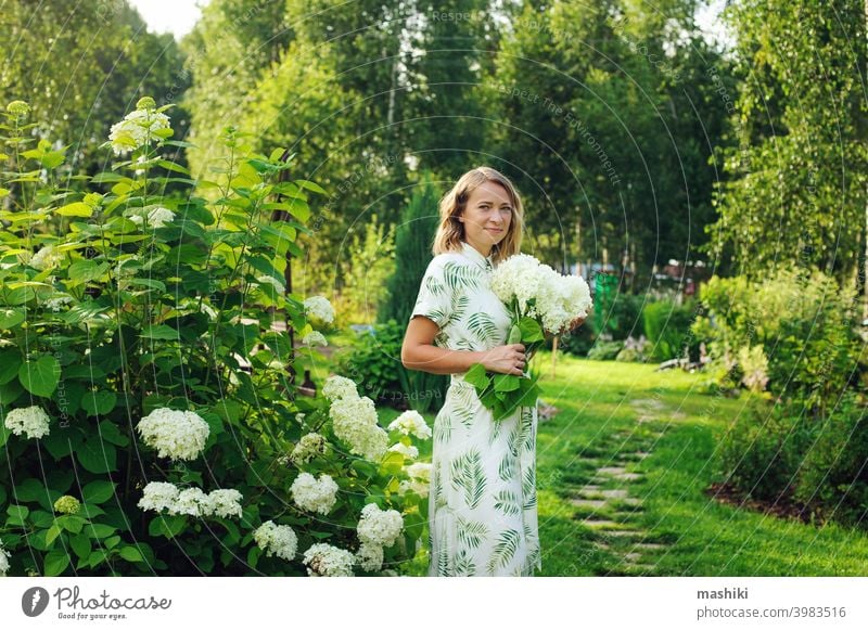 beautiful young woman gardener posing with hydrangea flowers in summer cottage garden person gardening outdoor plant female lifestyle nature adult girl smiling