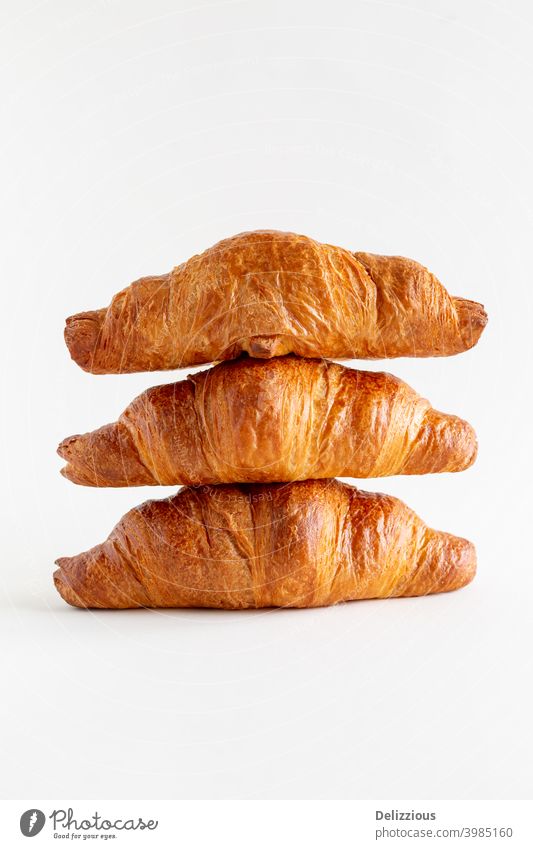 Three freshly baked croissants stacked on top of each other on a white background with copy space, close up baked pastry item bakery bread breakfast brown