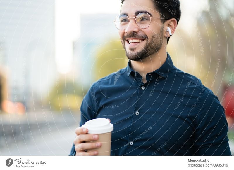 Young man holding a cup of coffee while walking outdoors. portrait young urban take away close up beverage one closeup ear buds leisure ear pods day