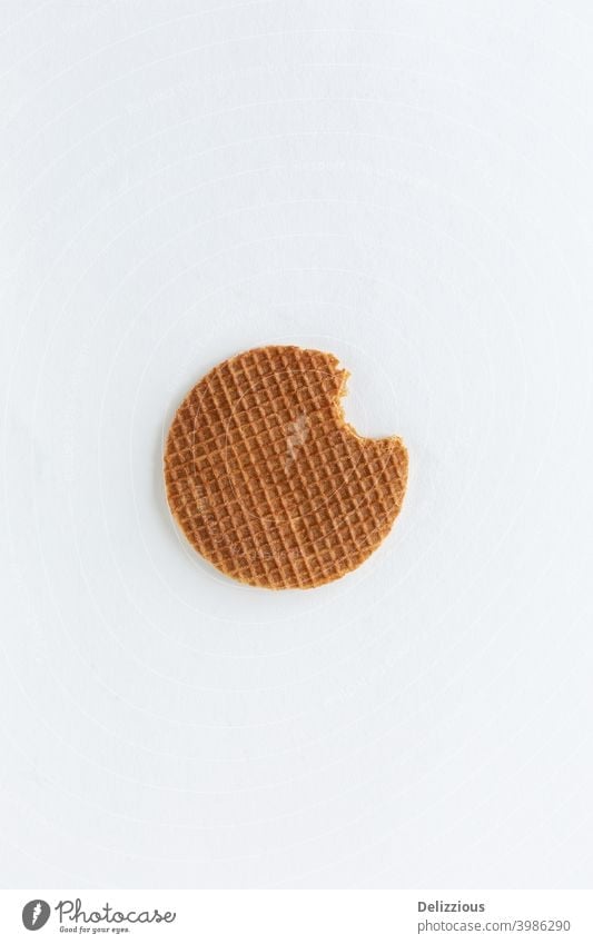 A single Dutch stroopwafel (syrup or caramel waffle) with a bite out of it on white background bake biscuit brown bunch butter circle closeup cookie delicacy