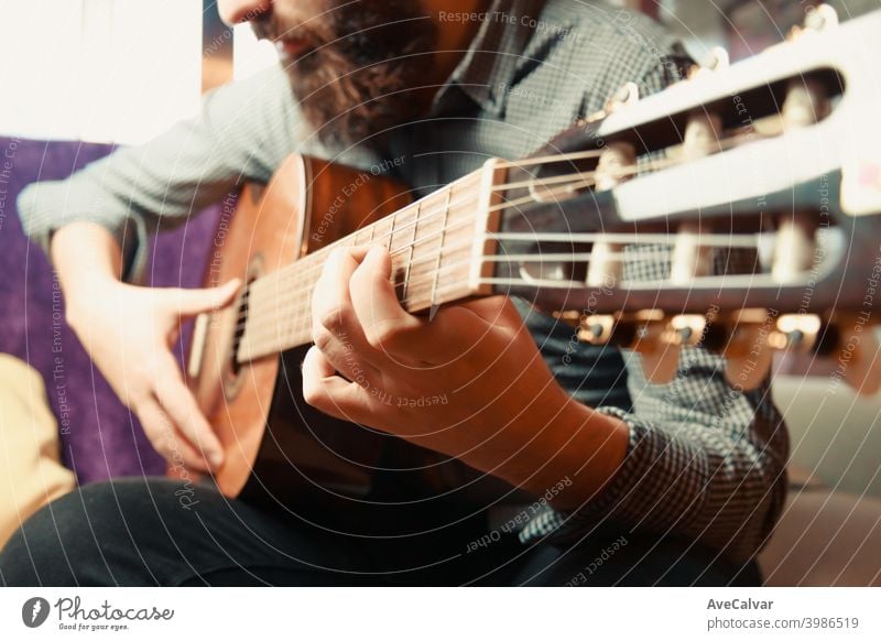 A close up of the hands of a bearded man playing the spanish guitar during a bright day acoustic guitar copy-space expressing funky harmony horizontal