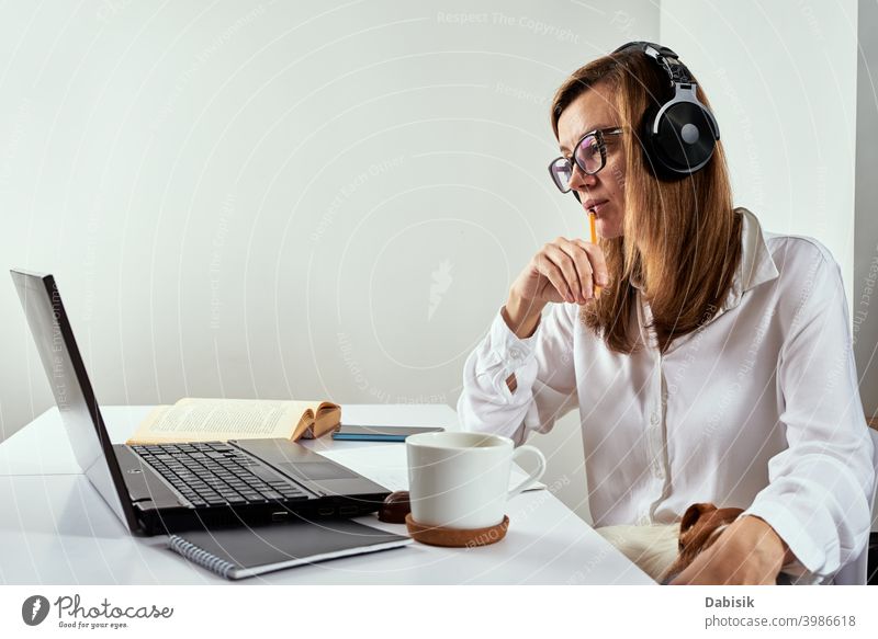 Remote work. Online cources, distance education and e learning concept. Woman in headphones listen audio course at laptop online remote study webinar conference