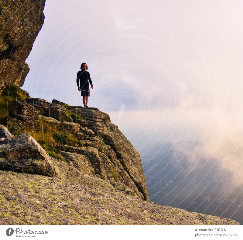 A man standing at clouds heights in the mountains next to a canyon Mountain summit hike sunset rocks colorful Height Panorama (View) Nature Landscape Sky Day