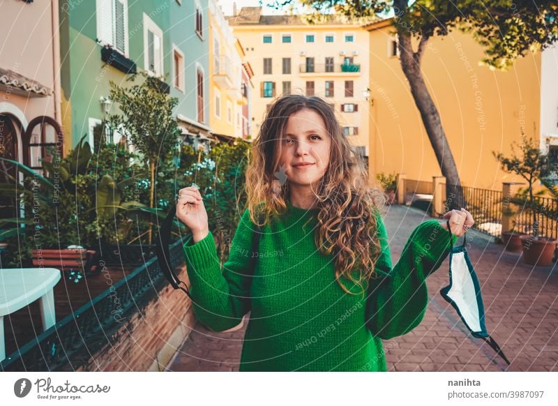 Young woman wearing green oversize sweater enjoying a windy day in a colorful city travel portrait lifestyle model europe european blonde female outdoors free