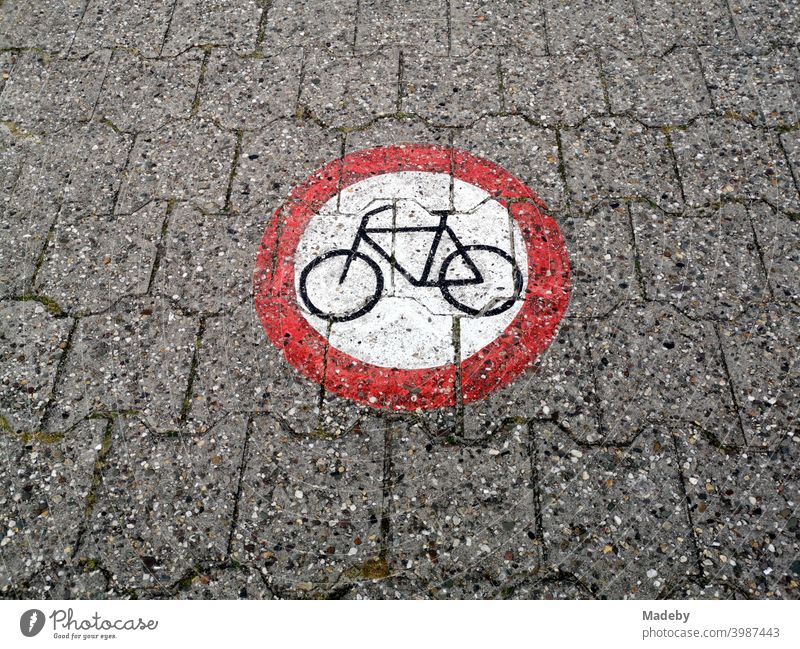 A round traffic sign painted on the composite pavement prohibits the passage of bicycles on the dyke at the harbour of Neuharlingersiel near Esens in East Frisia in the district of Wittmund in Lower Saxony