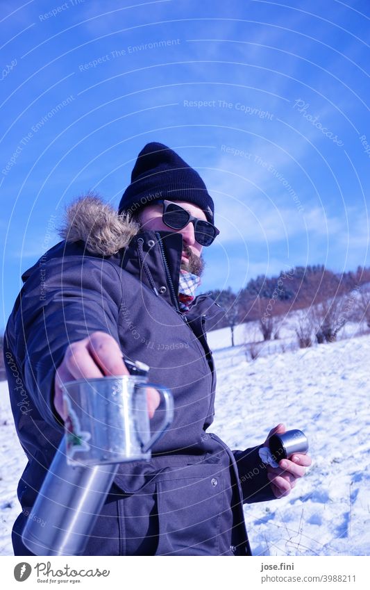 The tea pouring model, young man with sunglasses in the snow, teapot and mug in hand. Lifestyle Leisure and hobbies Outdoors Class outing Young man Landscape