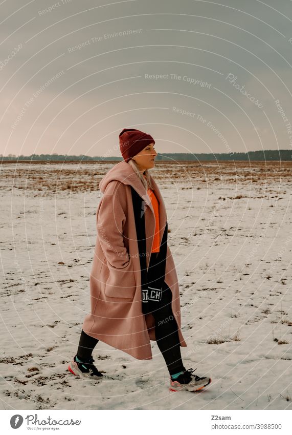 Fashionably dressed young woman goes for a walk stroll Winter wonderland Woman Young woman Coat To go for a walk Snow Sun Light Nature Landscape Scarf Cap