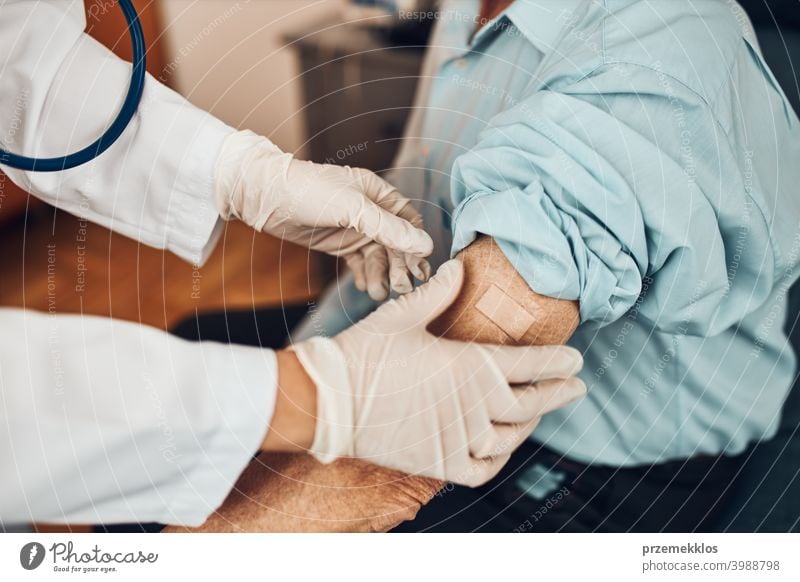 Doctor putting a plaster in place of injection of vaccine to senior man patient. Covid-19 or coronavirus vaccination person hospital doctor medical medicine