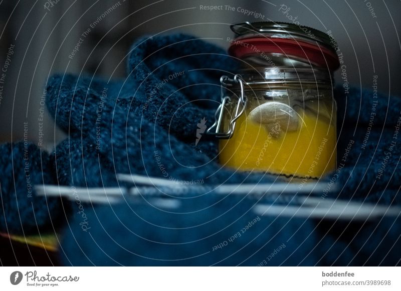 A filled honey jar stands as nerve food on a blue knitted work, focused on the jar with blurred foreground and background Knit Handcrafts Wool Knitting needles