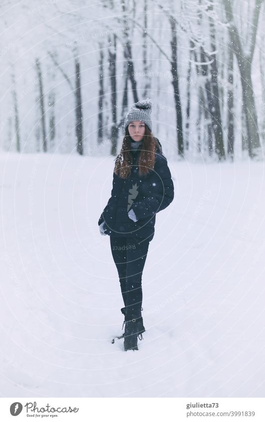 Portrait of teenage girl in winter snowfall standing in a snowy park Front view Looking into the camera portrait Girl teenager Colour photo Youth (Young adults)