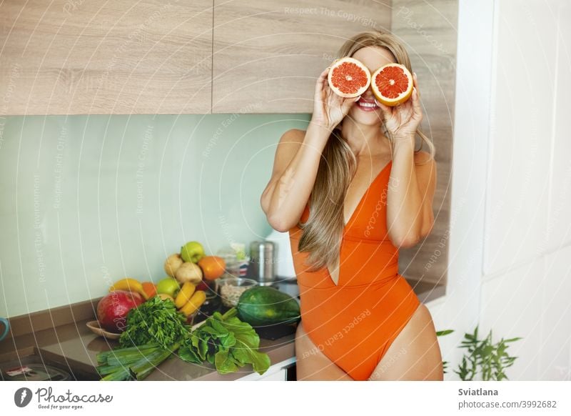 Portrait of a sporty girl with a grapefruit in her hands in the kitchen with fresh vegetables and fruits. The concept of a healthy lifestyle, health, beauty