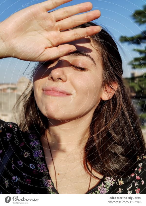 Girl with the eyes closed covering the sun with her hand. health dermatology female treatment worried sunshine hot facial summer wrinkle skin bright sunblock