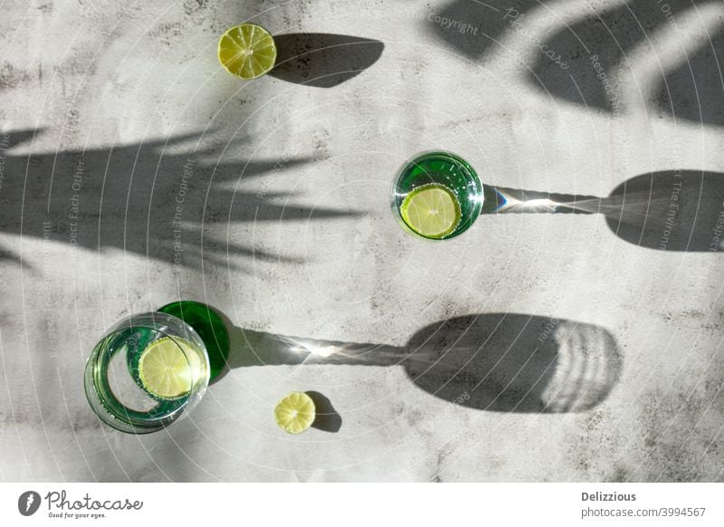 top down view of drinks and shadows with lime, tropical mood on light surface water ingredient white background citrus closeup cocktail cold concept copy space