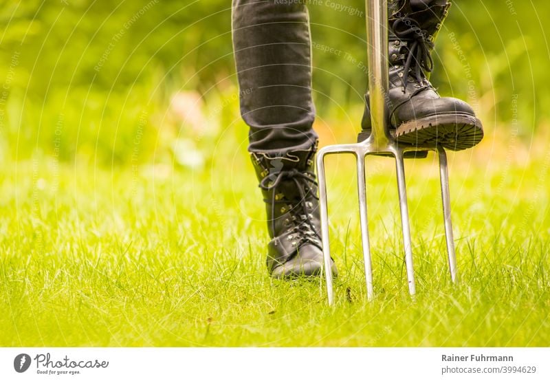 Close up of a gardener standing in a garden with his tools Garden Gardener digging fork Tool cultivate hobby free time Working shoes Footwear Gardening Green