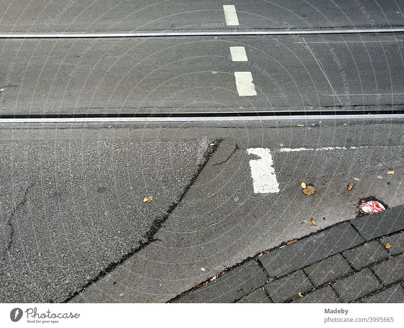 Old grey asphalt with tram tracks and white markings of a pedestrian crossing in Cologne on the Rhine in North Rhine-Westphalia, Germany Street Traffic lane