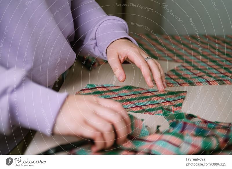 Closeup of female tailor cuting out checkered fabric with a paper pattern to make out a shirt tailoring woman sewing plaid cutting clothing textile cut out