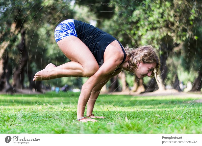 Yoga in the park, middle age woman doing bakasana exercise crane pose. adult balance beautiful body caucasian concentration female fitness grass healthy