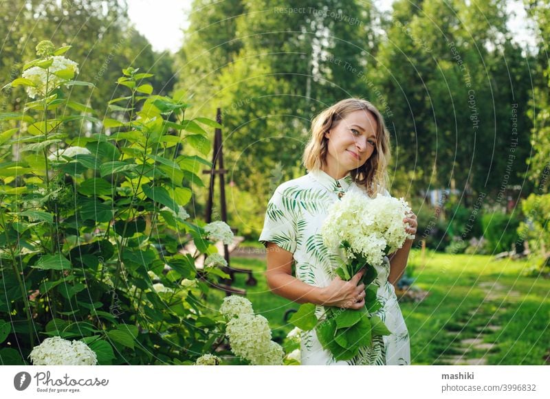 beautiful young woman gardener posing with hydrangea flowers in summer cottage garden person gardening outdoor plant female lifestyle nature adult girl smiling