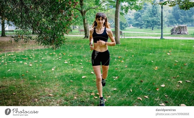 Female athlete running through a park runner woman training autumn sportswoman morning young female people fit healthy body exercise girl athletic fitness