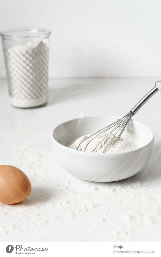 Cooking tools and ingredients flat lay with copy space. Baking header with measuring  spoons, wooden scoops, whisks, rolling pin, cookie cutters, sugar, flour,  eggs and cinnamon on a blue background. Stock Photo