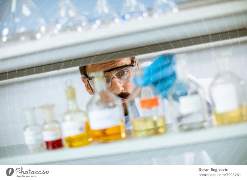 Young researcher with protective goggles checking test tubes analysis analyzing biochemist biochemistry biology biotechnology caucasian chemical development