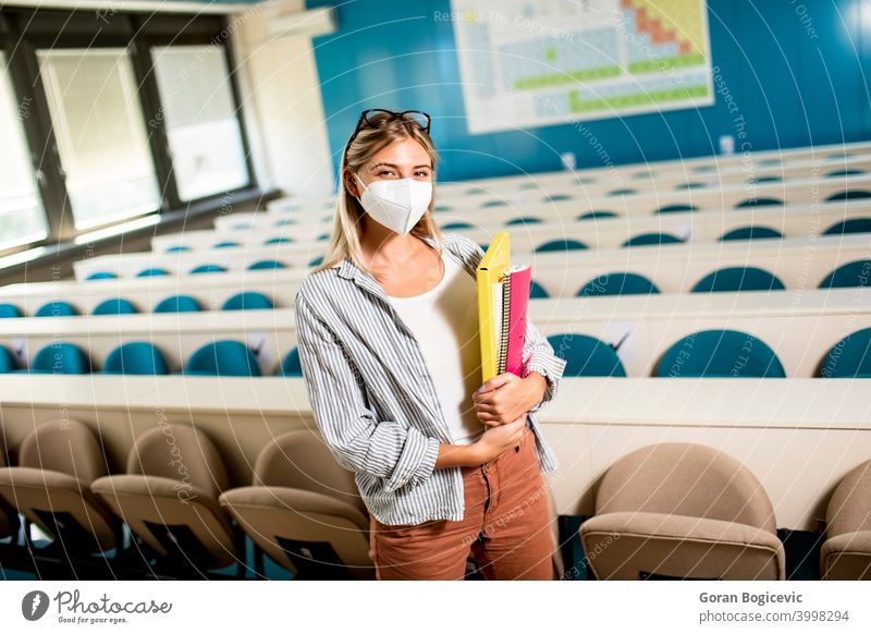 Female student wearing face protective medical mask for virus protection standing at lecture hall academic beautiful caucasian college concept corona