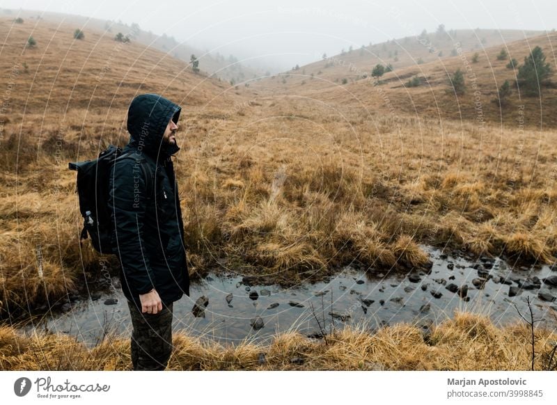 Young man exploring nature on a wet winter morning in the mountains adventure alone autumn backpack backpacker challenge cold exploration explore explorer fog