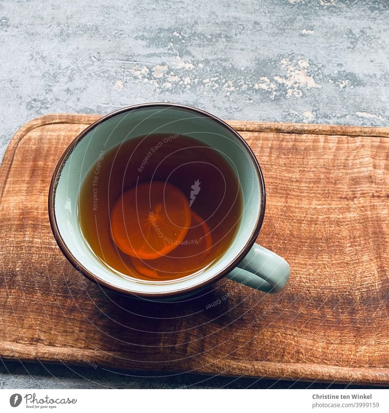 A cup of hot Darjeeling tea with lemon slices stands on a wooden board. Grey marbled background, shot from bird's eye view Tea Tea cup Darjeling Winter chill