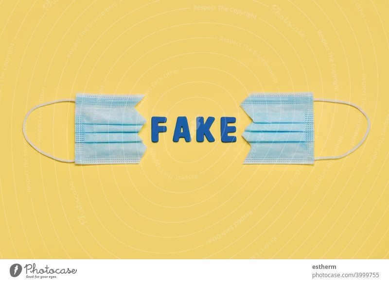 Protective surgical mask split in two with letters forming the word fake.Concept of protesting against coronavirus scams protective surgical mask