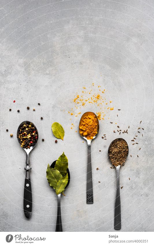 Variation of spices on spoons. Rustic background. Spoon variation Herbs and spices Silver Old Bay leaf Curry powder pepper Cumin picture background flat lay