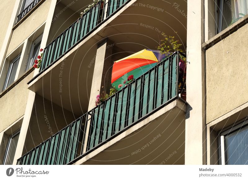 Colorful parasol on the balcony of a natural-colored tenement house in the style of the post-war period in the summer sunshine in Frankfurt am Main in Hesse, Germany