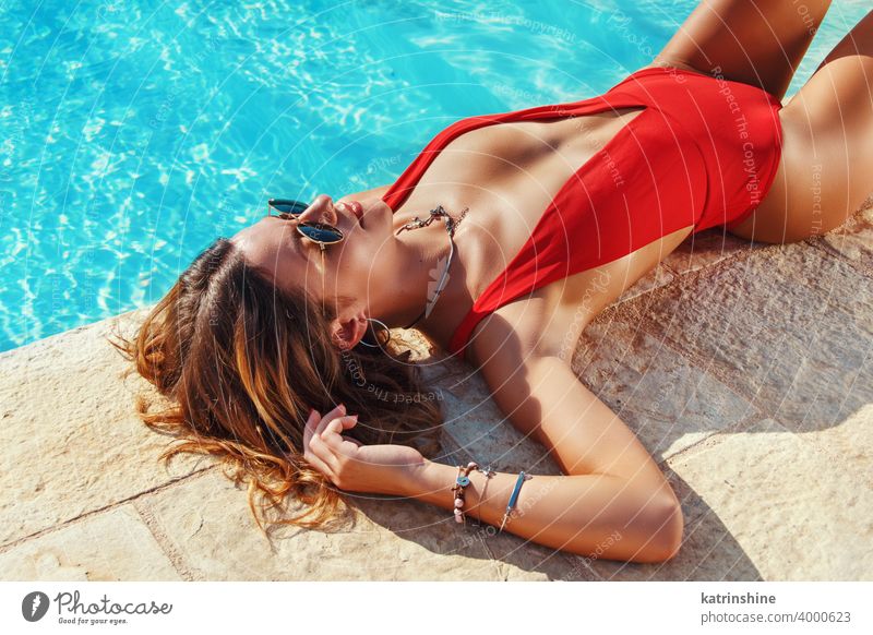 Young woman in red one-piece swimsuit relax beside a swimming pool tropical water Summer caucasian Fashion alone Outdoor Exotic Sensual copy space Beautyful