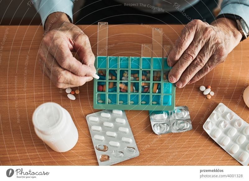 Senior man organizing his medication into pill dispenser. Senior man taking pills from box senior disease patient prescription medical medicine person