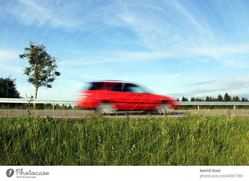 Speeding on German roads. A red car speeds along a road Driving Motoring Street Lawn Leadfoot swift quick fast and furious Germany Car Vehicle Transport