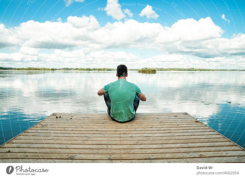 young man sits on a jetty in the nature and enjoys the absolute silence Footbridge Lake tranquillity Sit Man To enjoy gap Relaxation relaxation switch off