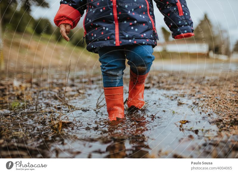 Child with red rubber boots playing on a puddle Rubber boots Red childhood Exterior shot Water Playing Weather Bad weather Dirty Boots Colour photo Day Joy