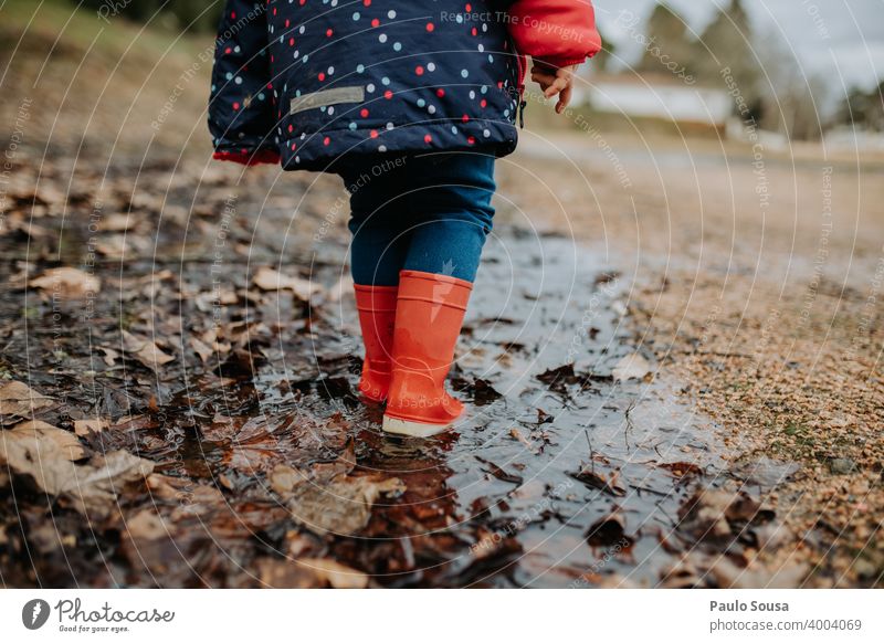 Low section child with red rubber boots walking on puddle Puddle Rubber boots Red Child childhood Authentic Playing Exterior shot Autumn Dirty Day Water Wet