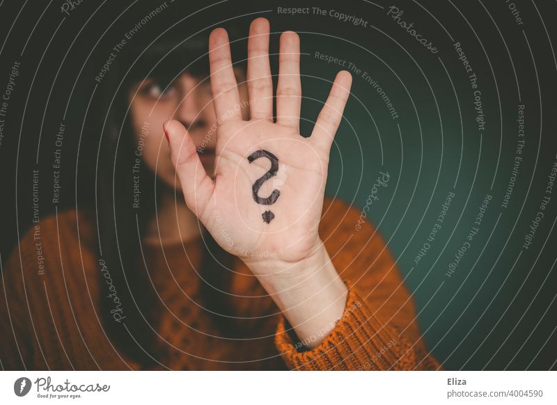 A woman holds up her hand, which has a question mark painted on it. Question mark Perplexed disorientation Identity insecurity Irritation Ask Insecure