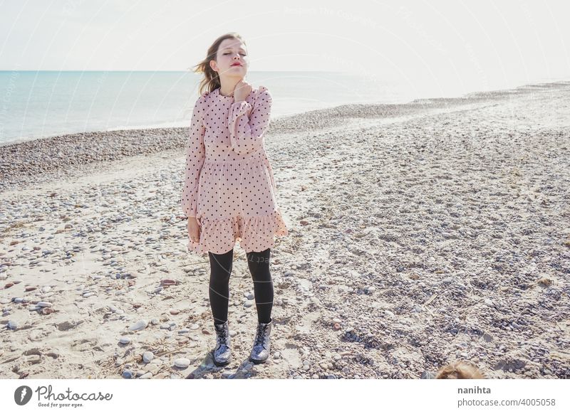 Young woman wearing a pink dress at the beach holidays trendy kawaii casual lifestyle blonde natural beauty attractive pretty fashion model wind windy sea shore
