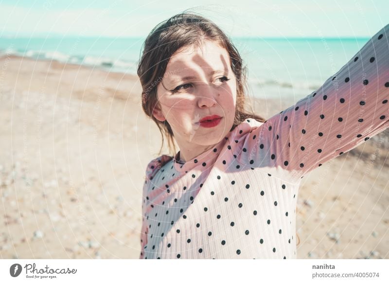 Young woman wearing a pink dress at the beach holidays trendy kawaii casual lifestyle blonde natural beauty attractive pretty fashion model wind windy sea shore