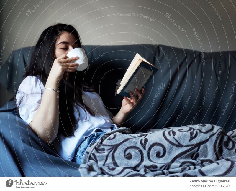 Woman drinking from a cup of coffee and reading a book female relax warm soft cute rest beautiful happy young living woman interior relaxation window people