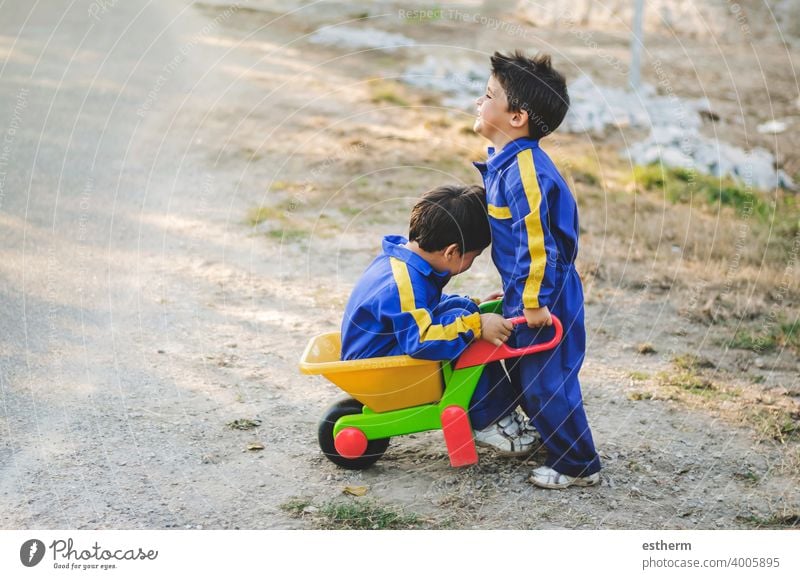 cheerful and smiling children are having fun in the field with a pushcart brothers siblings twins happy smile friendship elementary primary babies kid toddler