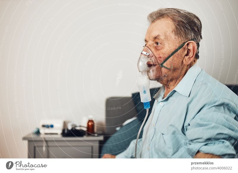 Senior man inhaling airways and lungs applying medicine. Covid-19 or coronavirus treatment. Man breathing through face mask using nebuliser patient person